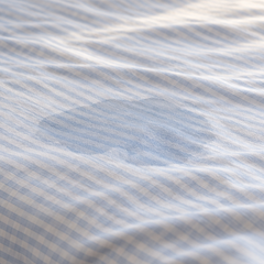 A small damp patch on a child's bed sheet